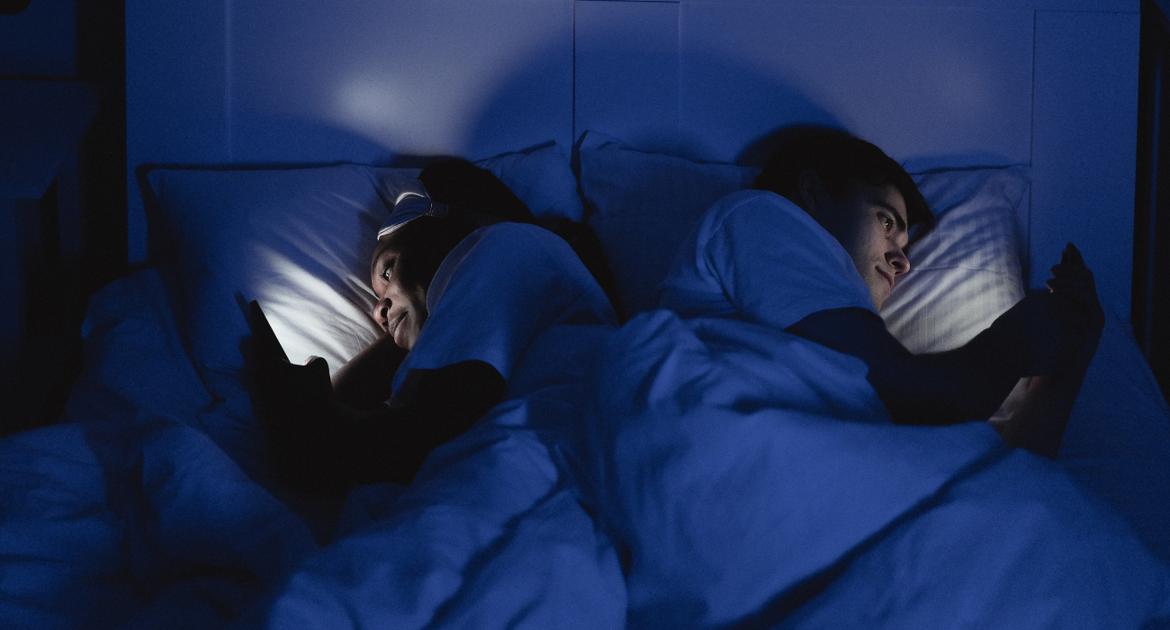 a couple using phones in bed